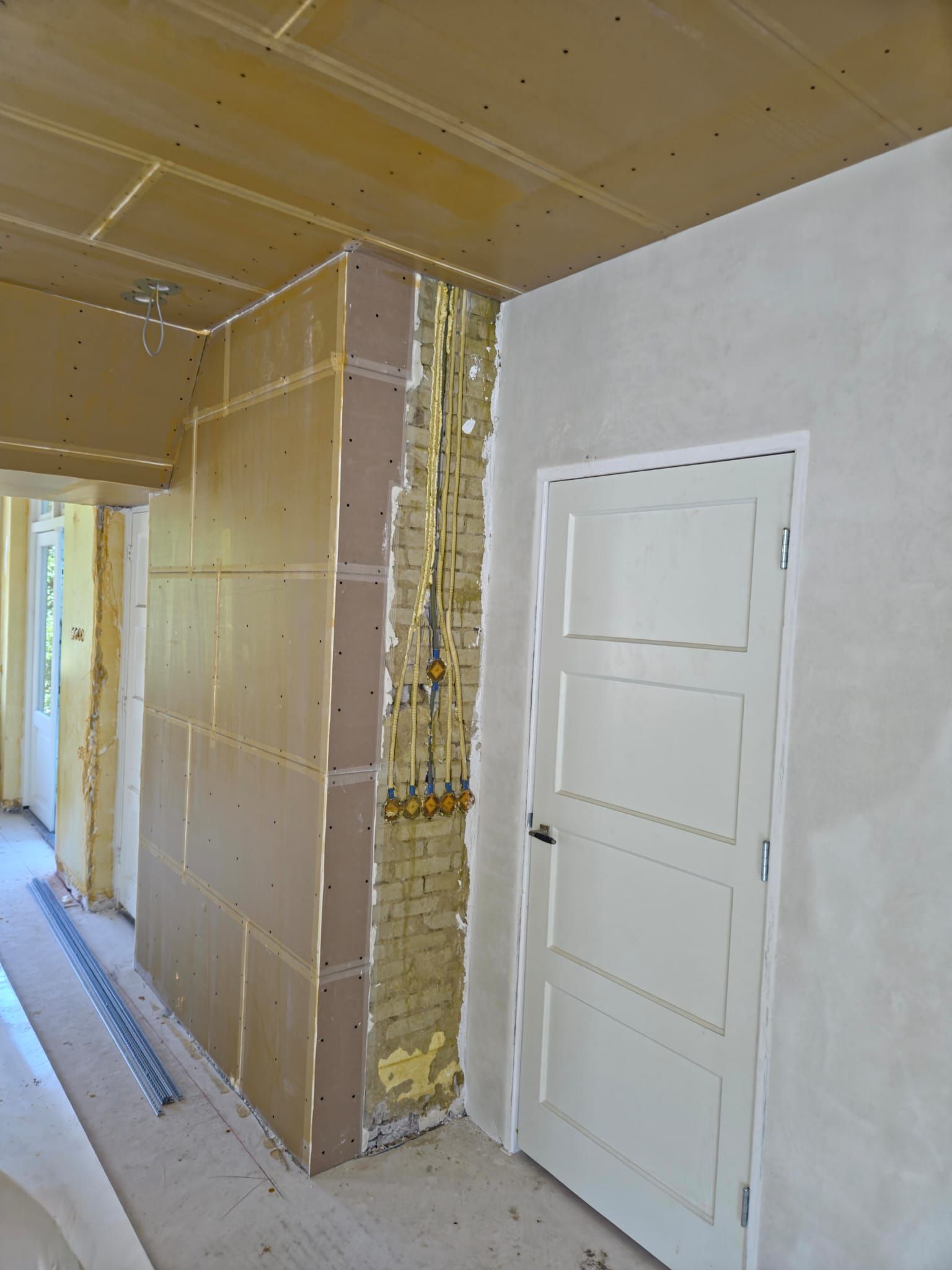 Werk in uitvoering: flexibele leidingen en inbouwdozen in een bakstenen muur tijdens een renovatie